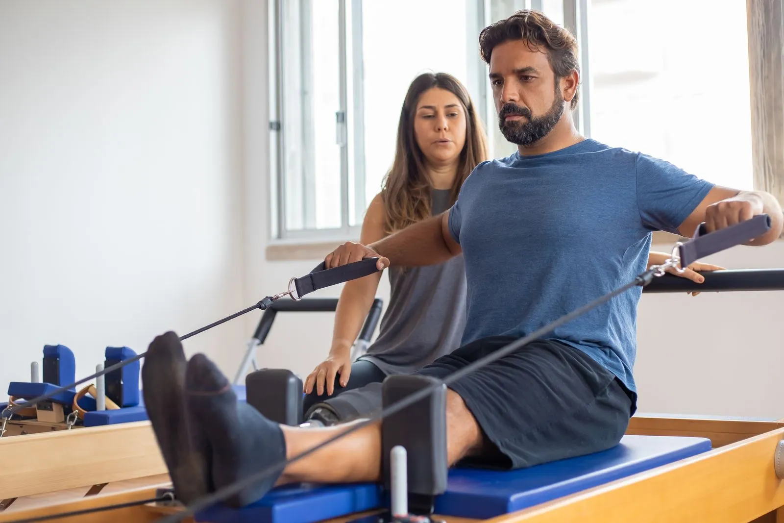 Instrutora acompanhando um aluno no aparelho de pilates